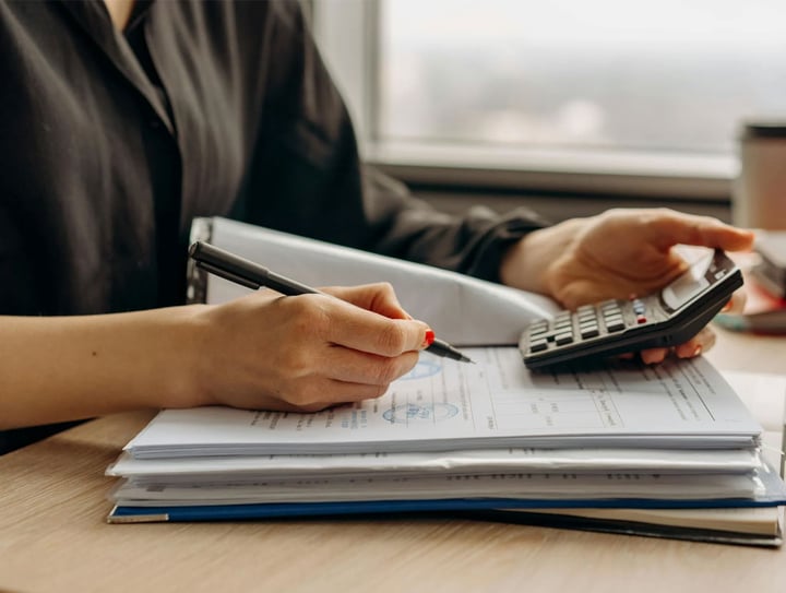 Person reviewing financial reports with a calculator