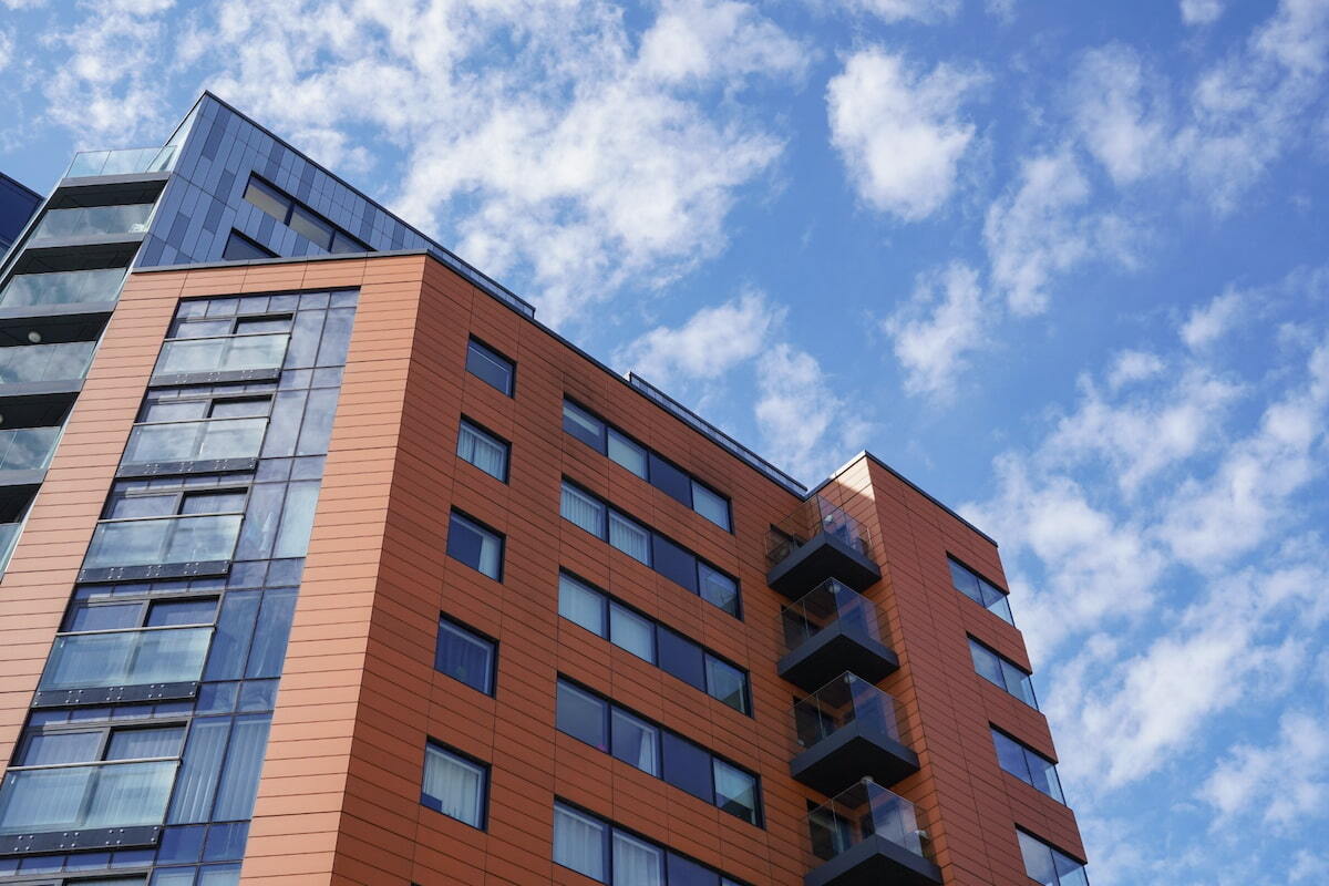 modern-red-cladded-apartment-block-balconies-blue-sky